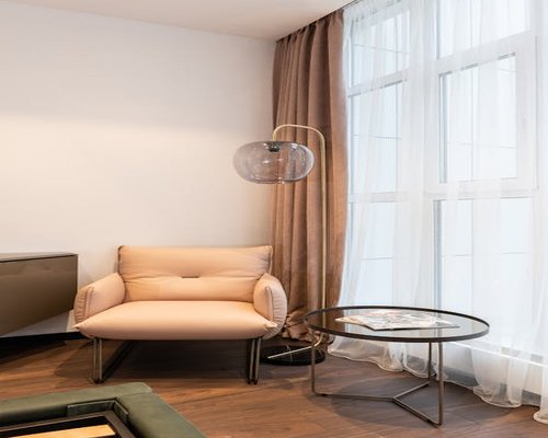 A well-arranged side-lit reading corner with soft fabric window curtains diffusing sunlight