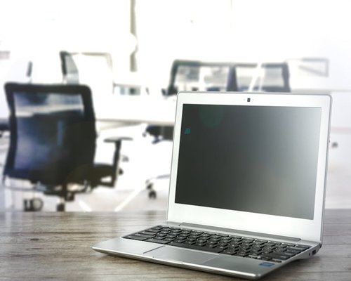 A laptop open on a table with soft background contrast highlighting ergonomic viewing distance