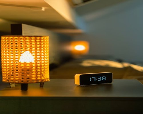 A smart phone displaying adaptive warm light settings in a low ambient light bedroom interior
